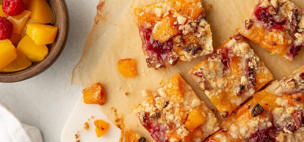 This recipes with canned peaches also calls for raspberries all baked over a shortbread crust then sliced into squares to serve.