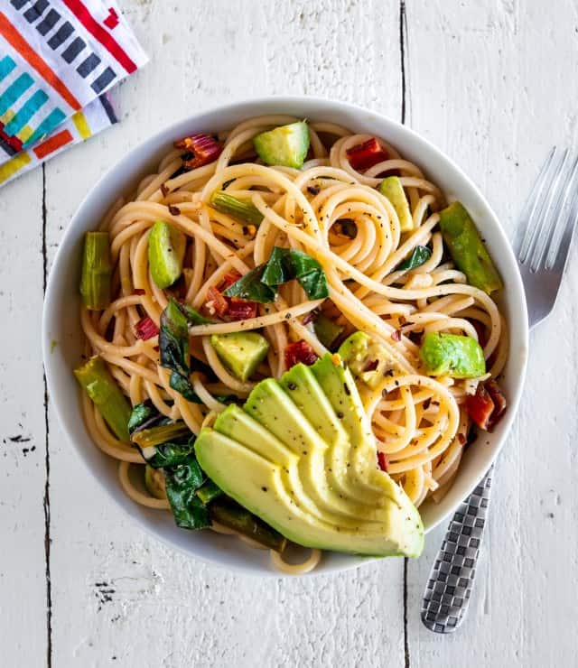 A bowl of Spaghetti with Asparagus, Wilted Greens, and Avocado. This recipe sauces the asparagus which is one of the best ways to cook asparagus.