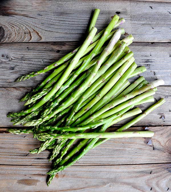 Fresh asparagus spears lying on wood background.