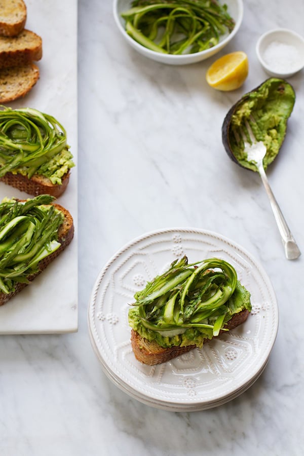 Shaved asparagus is one of teh best ways to cook asparagus. Shaved asparagus is piled on top of a piece of avocado toast and dressed with cilantro tahini .