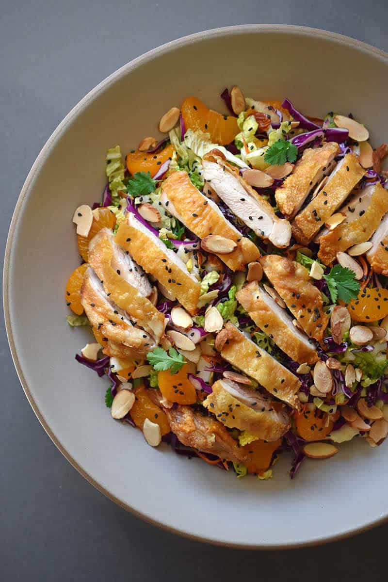 A bowl oc Chinese chicken salad topped with slices of crispy chicken