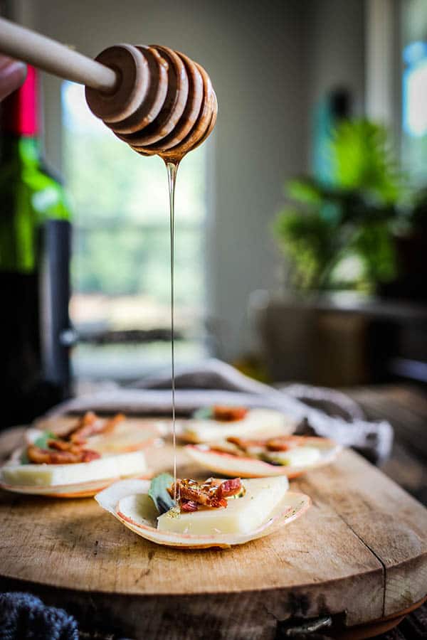 Honey being drizzled on an apple stack. with basil and bacon. This is how to use honey!