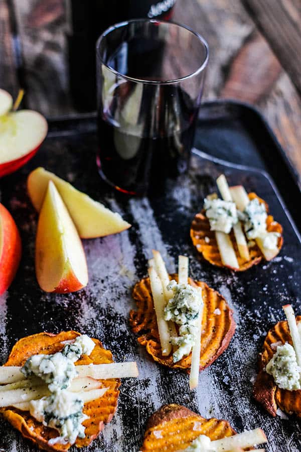 California Sweet Potato Rounds with crumbled blue cheese and matchstick apple slices on top paired with a glass of red wine.