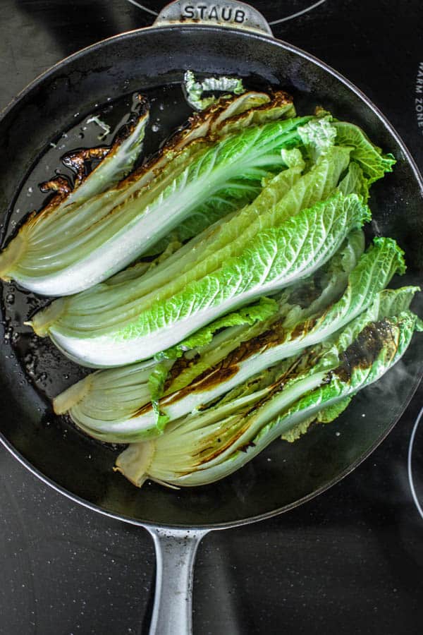 Napa cabbage wedges being seared in a cast iron skillet for Melting Napa Cabbage recipe 