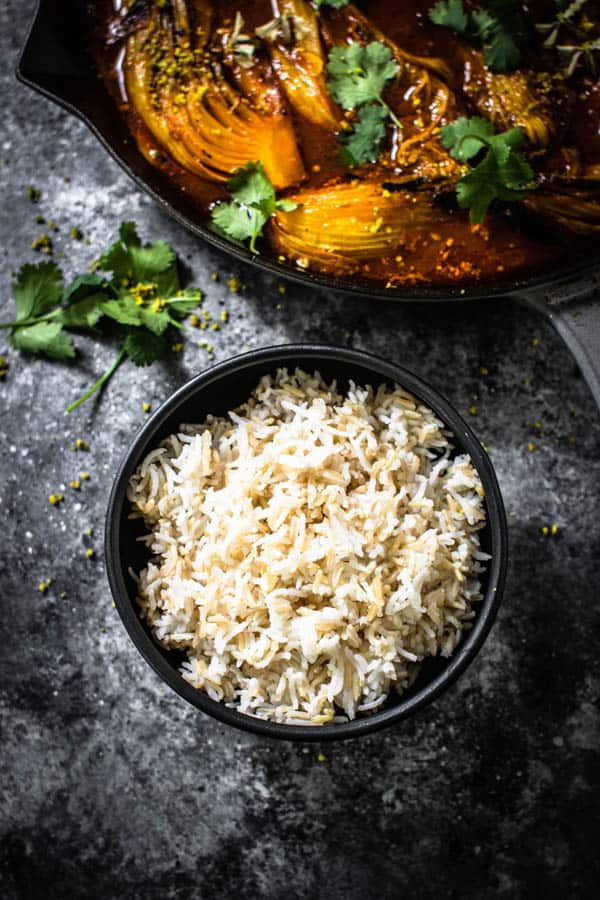 A bowl of 50/50 rice - half white rice, half brown rice next to a skillet of Melting Napa cabbage ready to be served.