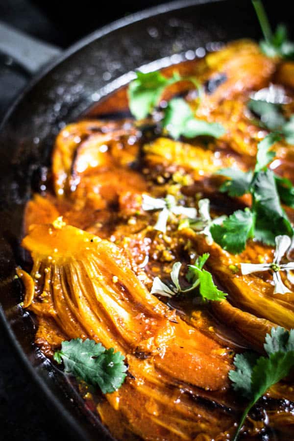 Melting Napa Cabbage recipe topped with cilantro leaves, pistachio crumble, and arugula flowers