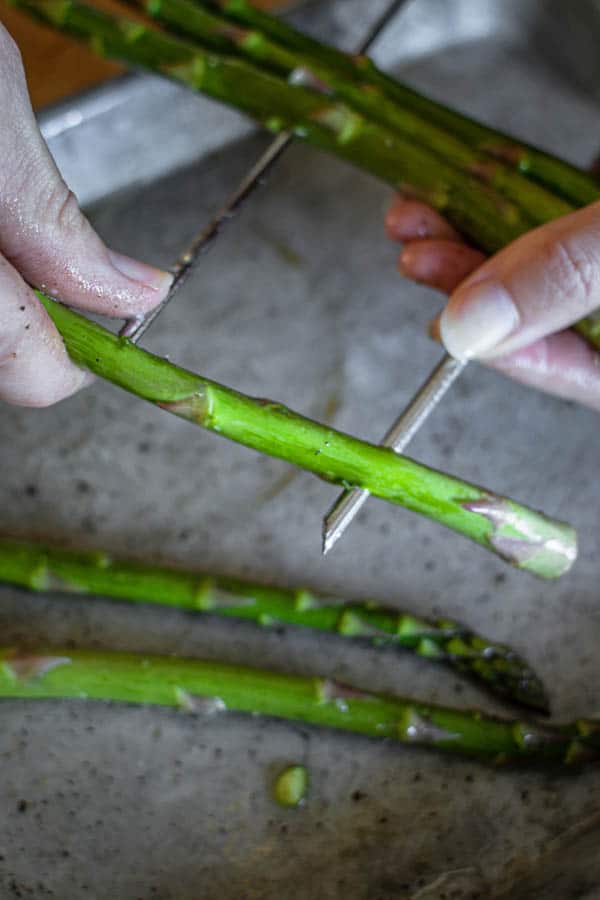 A second metal skewer being threaded into the asparagus spears. This is how to grill asparagus so that you do not loose any spears in the grates of the grill. 