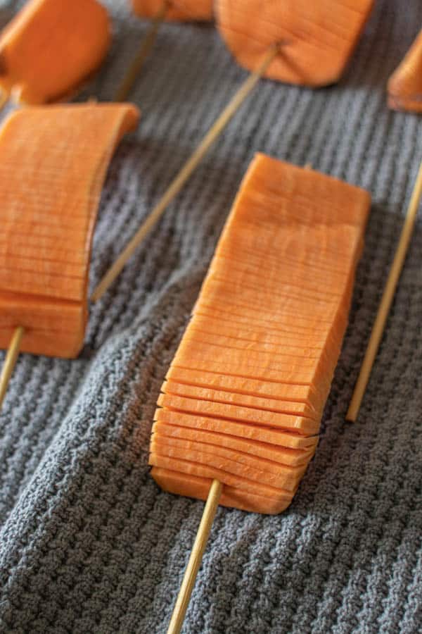 Hasselback Sweet Potato Skewers drying after soaking on kitchen towel.