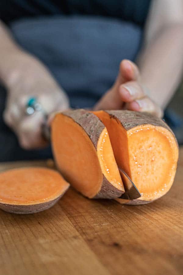 A sweet potato being broken down into slabs for Hasselback Sweet Potato Skewers .
