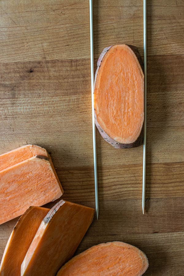 A slab of sweet potato placed between two wooden skewers to make Hasselback Sweet Potato Skewers.
