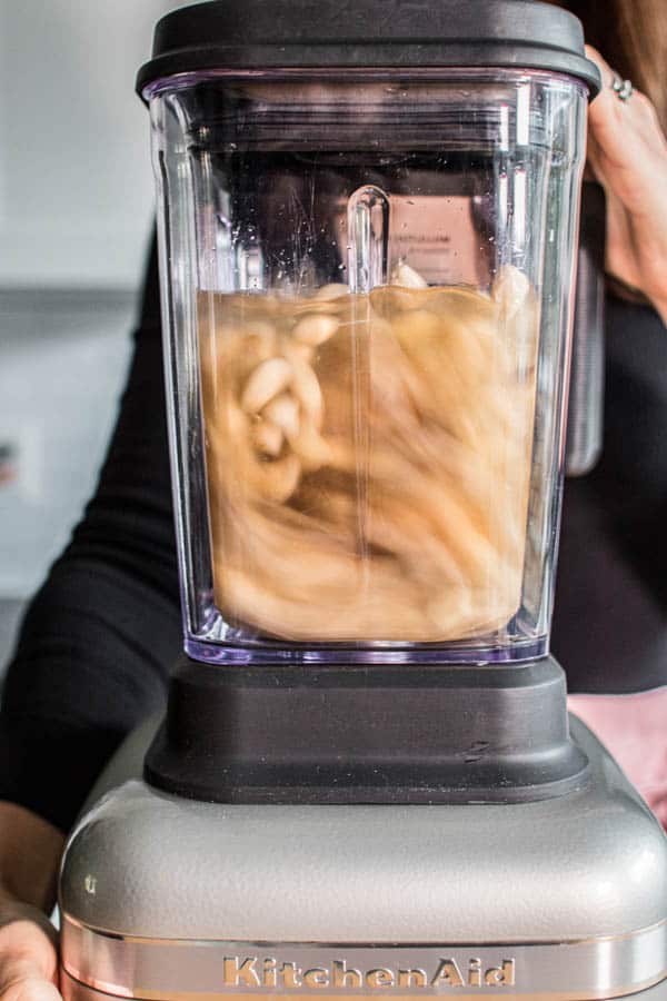 This is how to make almond milk, all of the ingredients are being blended together in a blender until smooth and creamy. 