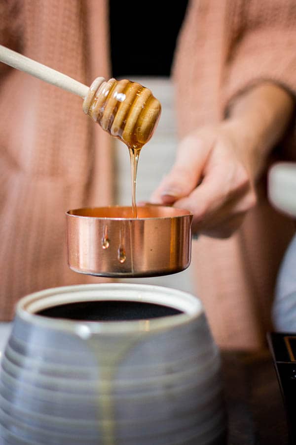 Measuring honey in a measuring cup with a honey dipper. 