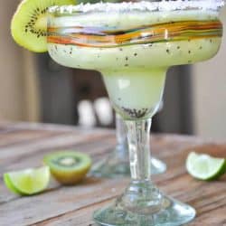A colorful margarita glass filled with a kiwi margarita. This recipe with kiwi also calls for a kiwi garnish on the rim.
