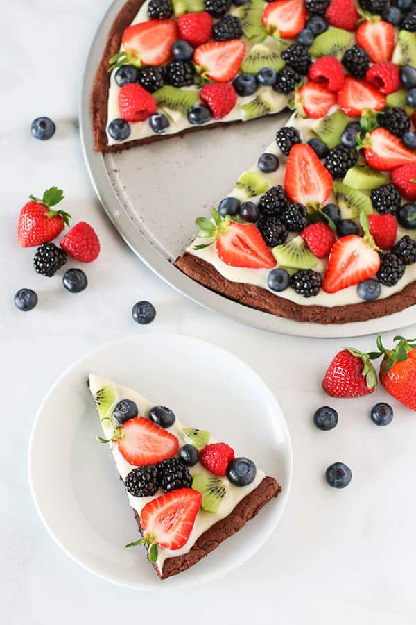 A round Brownie Fruit Pizza  topped with a vegan whipped topping 