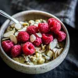 A bowl of Pistachio Wild Rice Pudding topped with raspberries and almonds. this easy recipe for rice pudding is worth the effort.