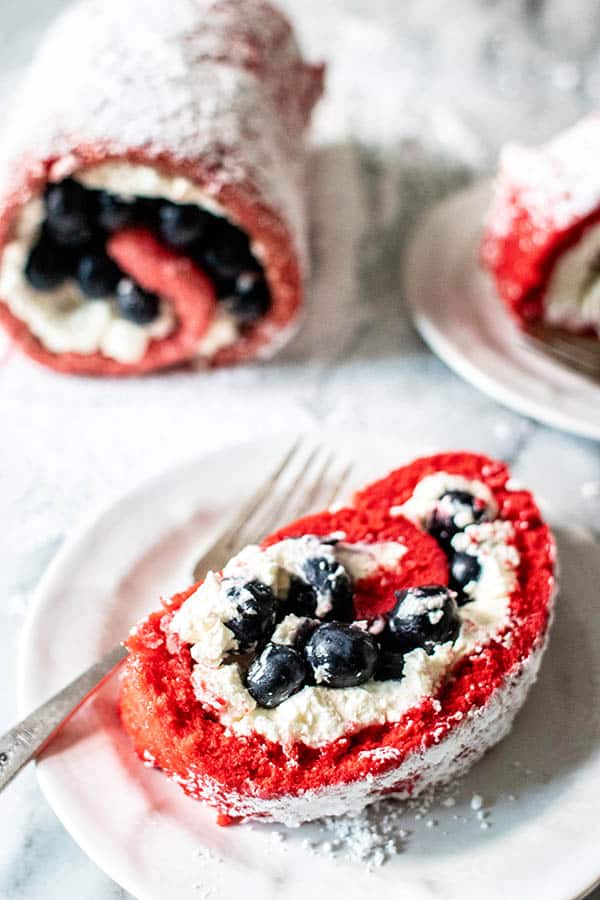 A red, white, and blue dessert cake roll. Red cake rolled up with fresh whipped cream and blueberries. 