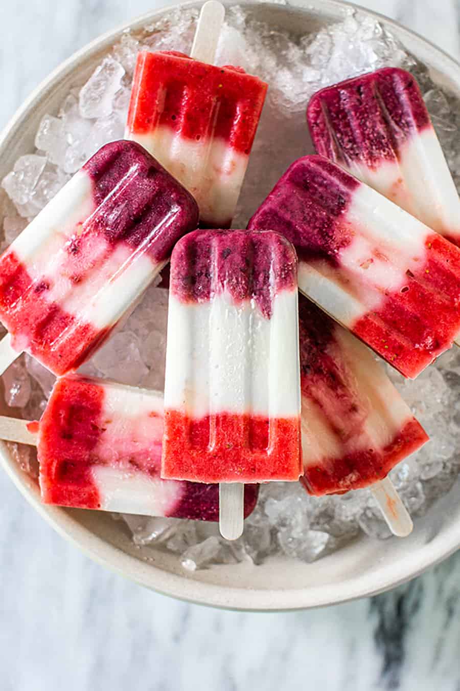 7 red, white, and blue popsicles in a bowl of ice.
