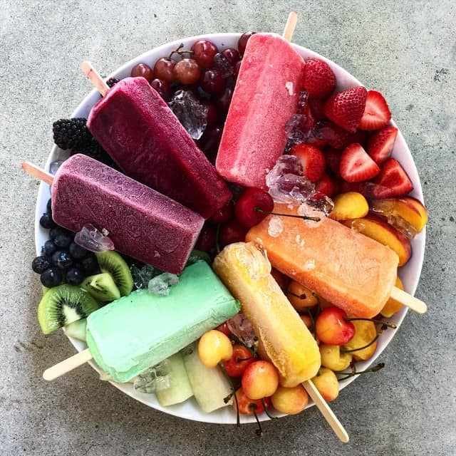 A colorful Rainbow Paletas and Fresh Fruit Board. Styled in a color wheel. 