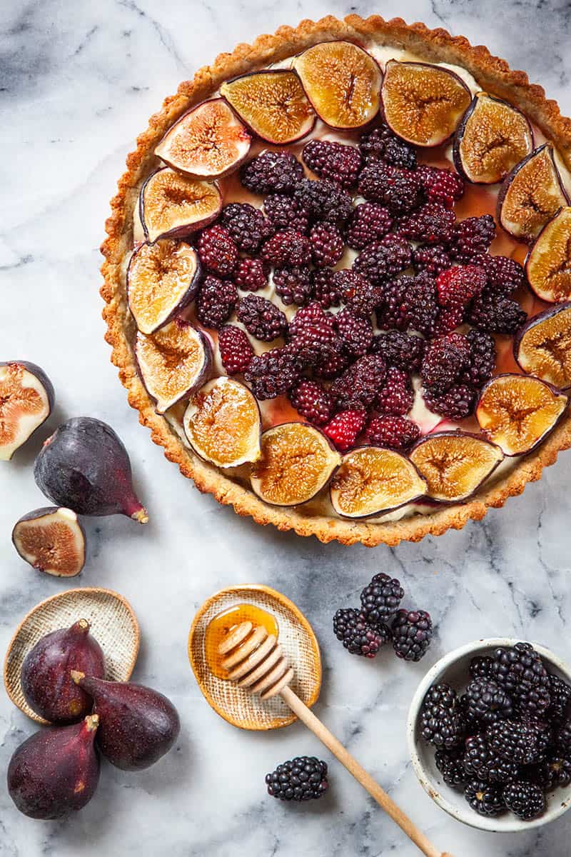 Berry Fig Tart recipe ready to serve with honey for drizzling.