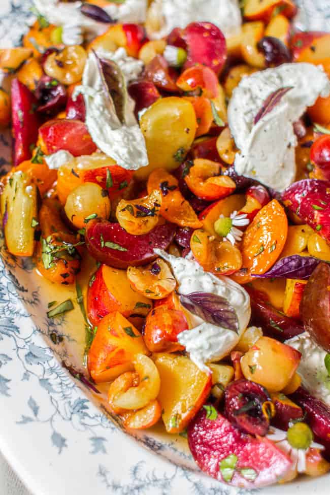 Close up of a stone fruit salad with burrata cheese.