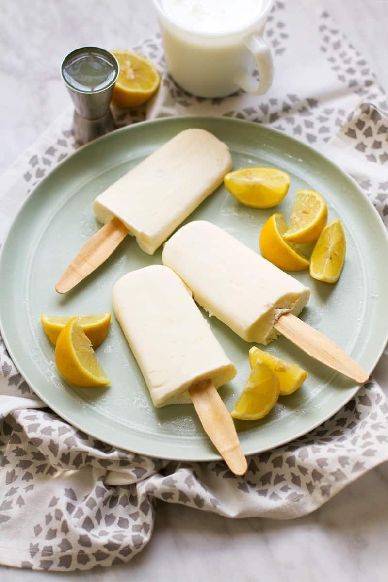 Limoncello Creamsicle Popsicles on a plate surrounded by orange wedges. 