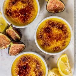 Ramekins of Fresh #Fig Compote and Easy Crème Brûlée on a table with fresh halved figs and lemon slices.