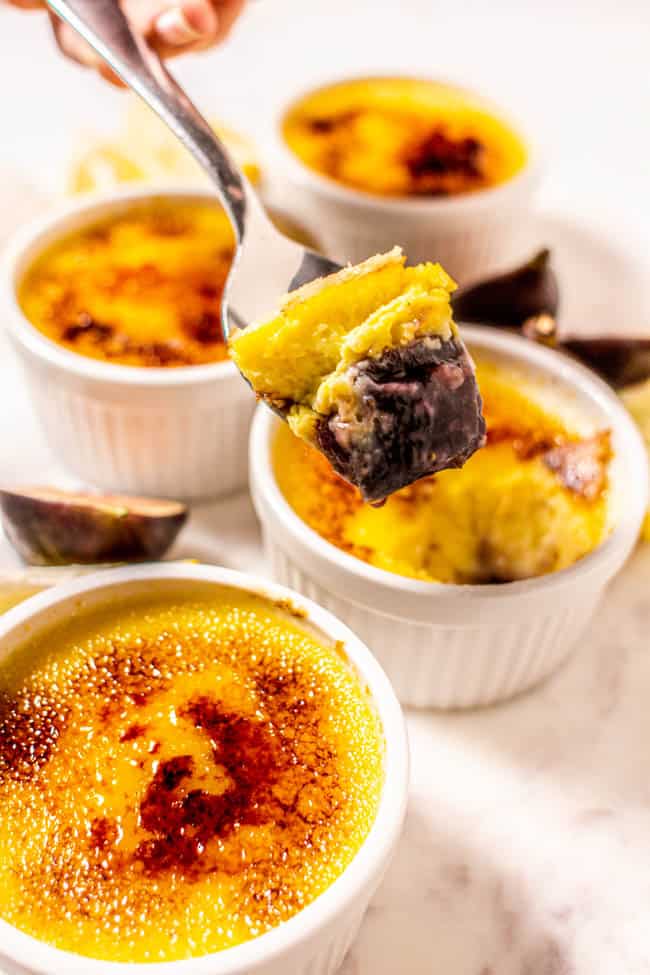 Someone taking a spoon full of Fresh #Fig Compote and an Easy Crème Brûlée. You can see the fig compote on the bottom of the ramekin and the creme brulee on top.