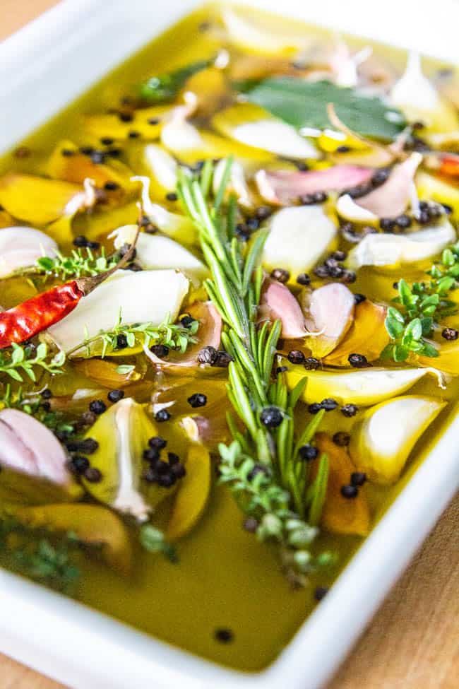 Garlic confit ingredients submerged in oil in a baking dish.