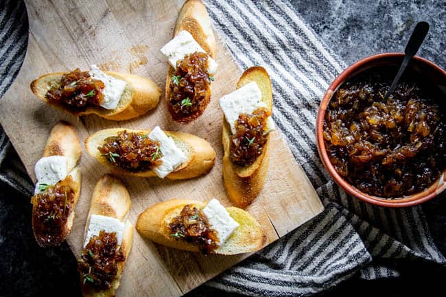 Sweet onion jam in a bowl and crostini with slices of breakfast cheese and sweet onion jam on top.