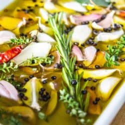 Garlic confit ingredients submerged in oil in a baking dish.