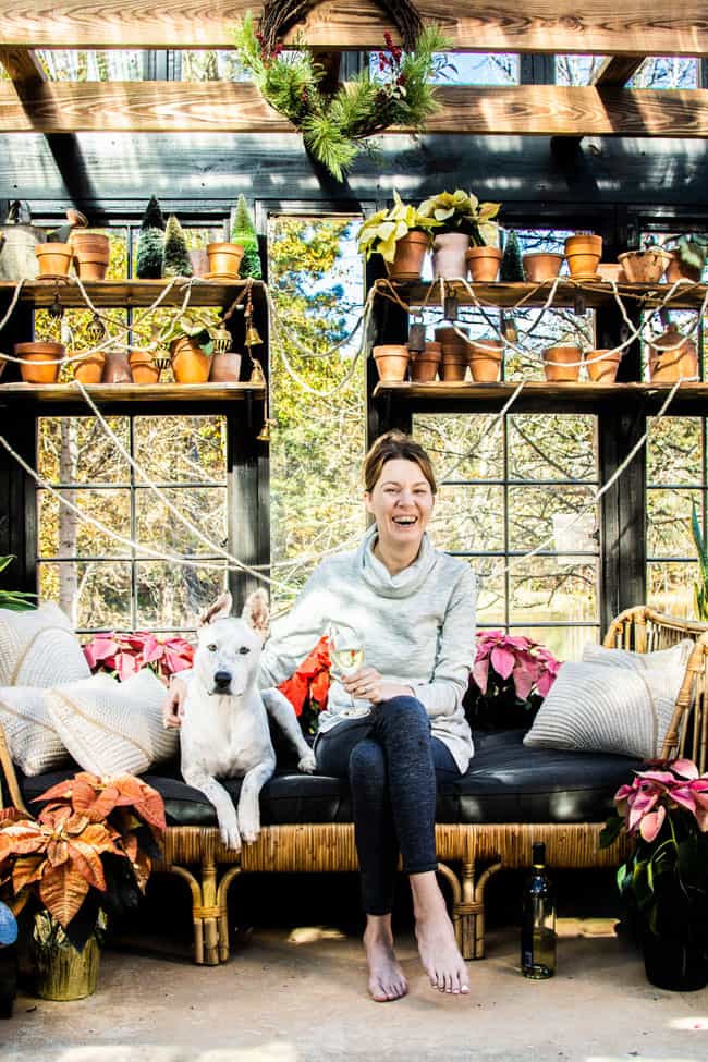 A woman and her dog in a greenhouse decorated with poinsettias.