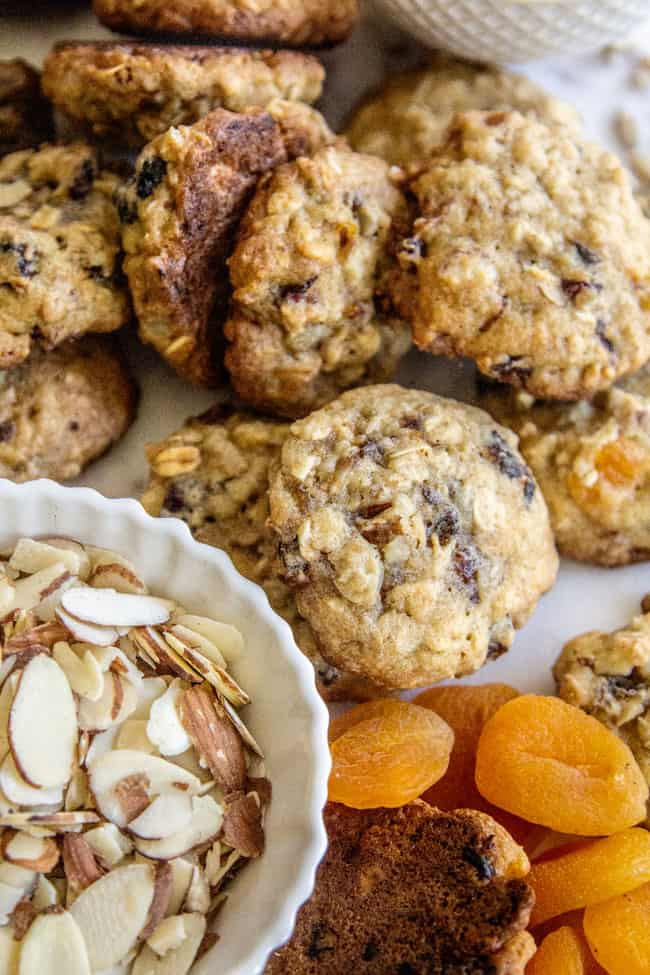 A pile of Oatmeal Breakfast Cookies next to slivered almonds and dried apricots.