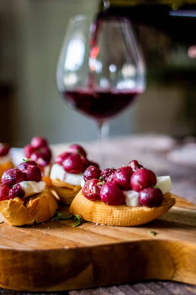 Roasted Jammy Grape and Brioche Crostini with red wine in the background.