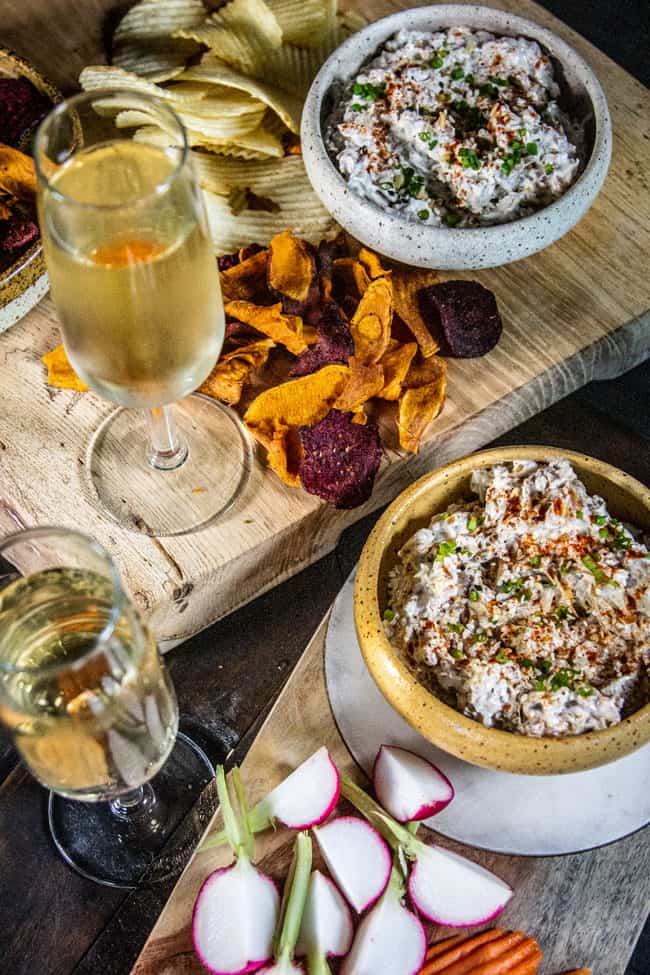 A recipe for onion dip served in two bowls with chips and crudite.