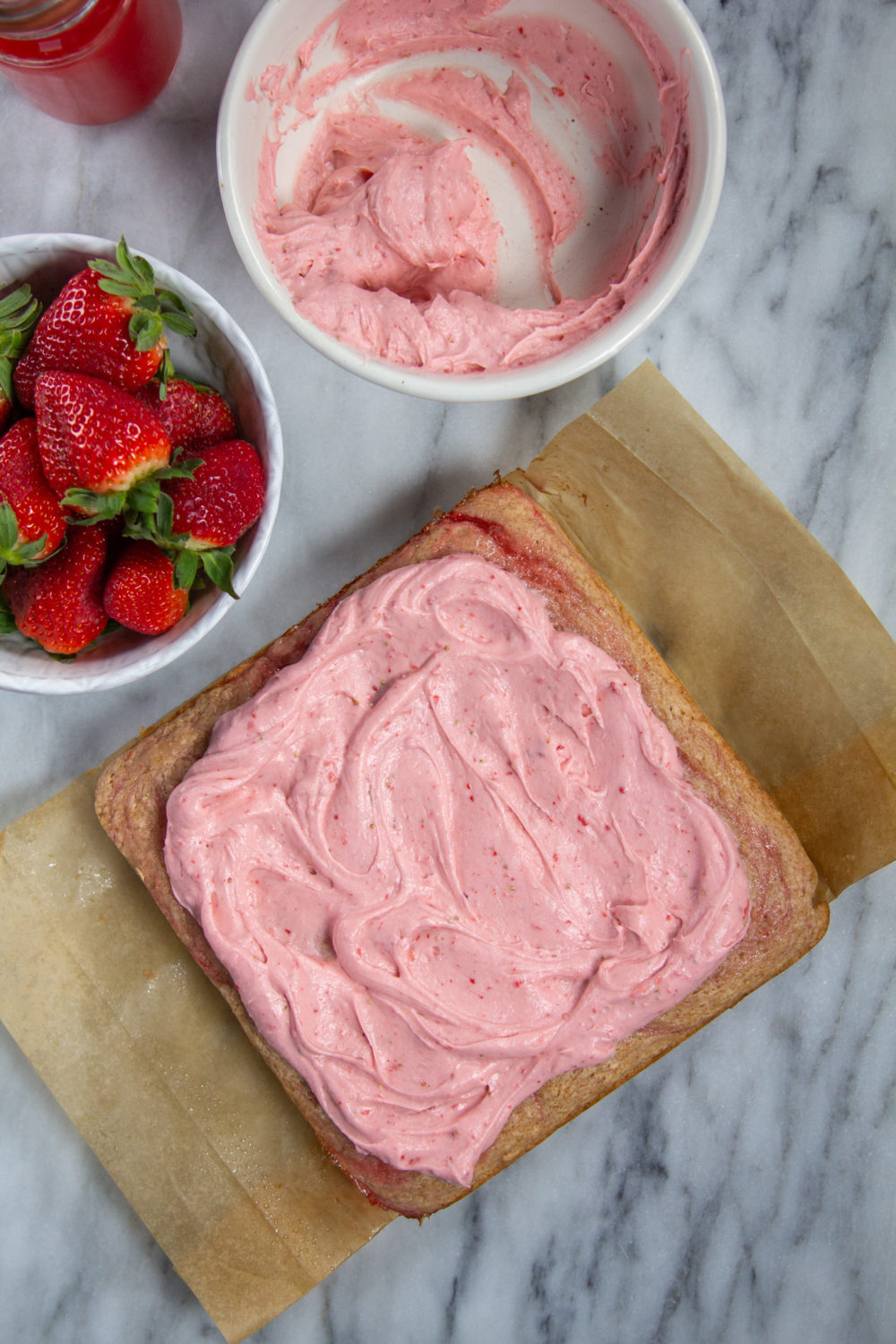 Iced Strawberry Rosé Snack Cake with a bowl of berries.