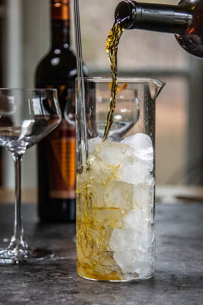 Vermouth being poured into a mixing glass.