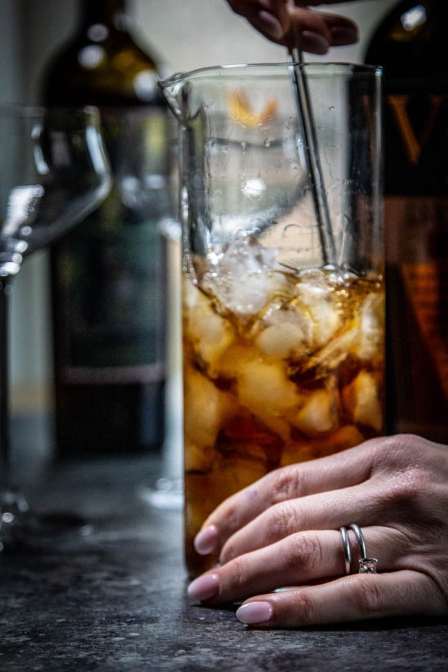 Adonis cocktail ingredients being stirred in a bar glass.