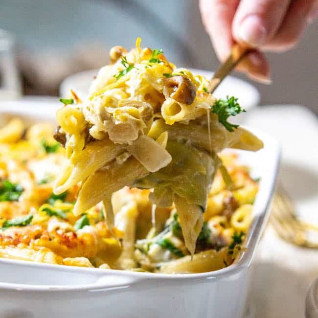 A woman serving Spinach and Artichoke Pasta Bake.