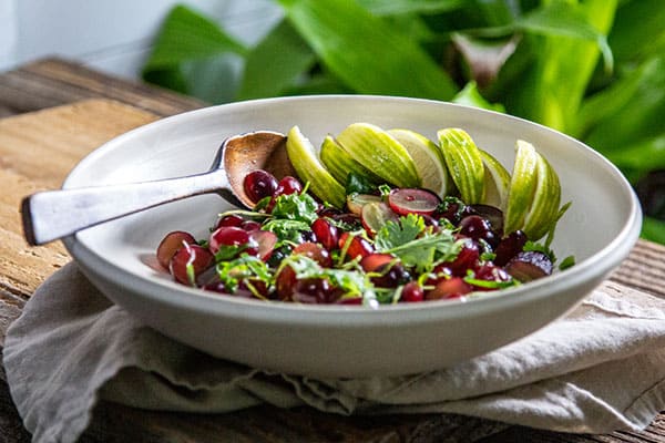 Sweet and Savory Grape Salad with lime wedges in a white bowl. 