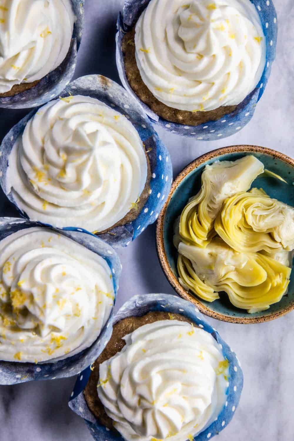 Lemon-Laced Artichoke Cupcakes next to a bowl of artichoke hearts.