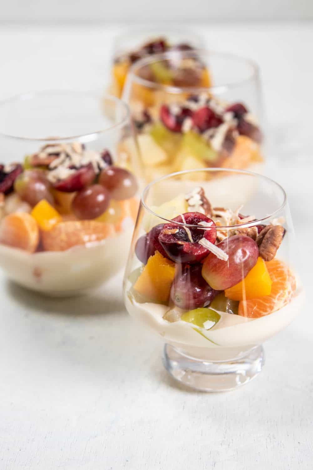 Four individula cups of layered Ambrosia Salad.