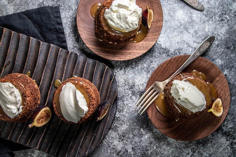 Four figgy puddings with caramel sauced and whipped cream.