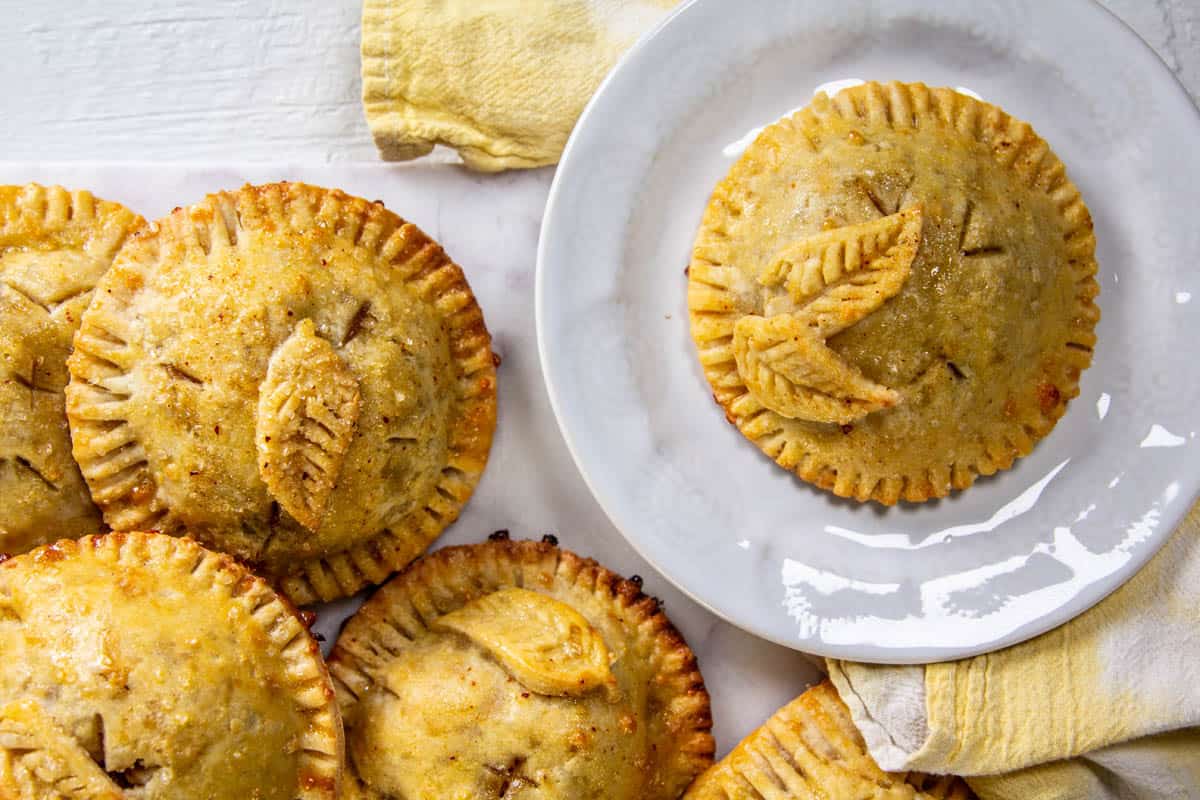 Round apple cheddar hand pies with decorative cut out leaf detail on top.