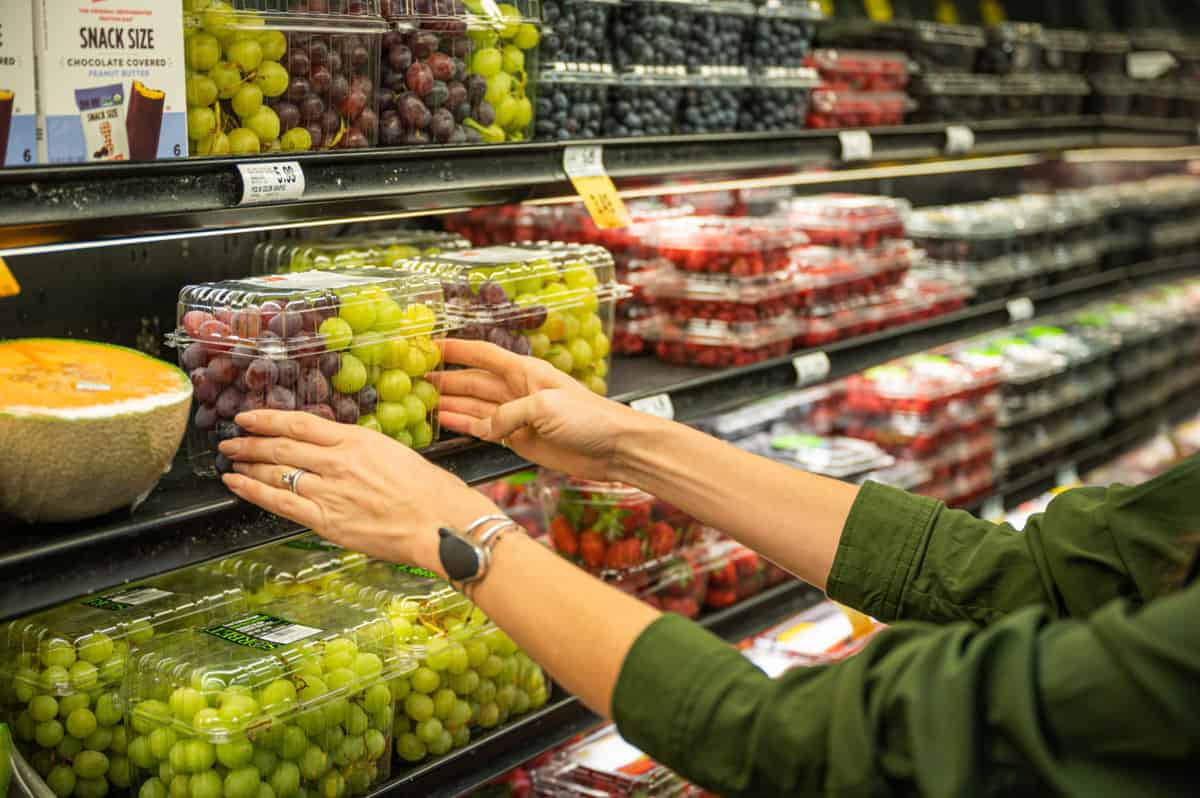 Customer looking at a clamshell of grapes in a grocery store
