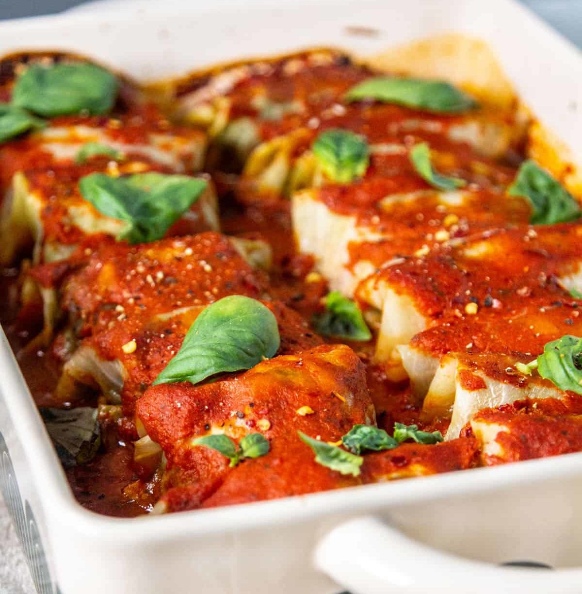 Cabbage rolls fresh from the oven with basil leaves.