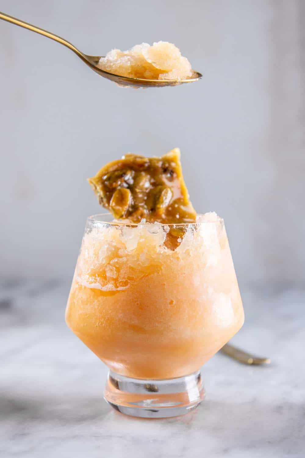 Cantaloupe granita shown on a golden spoon.