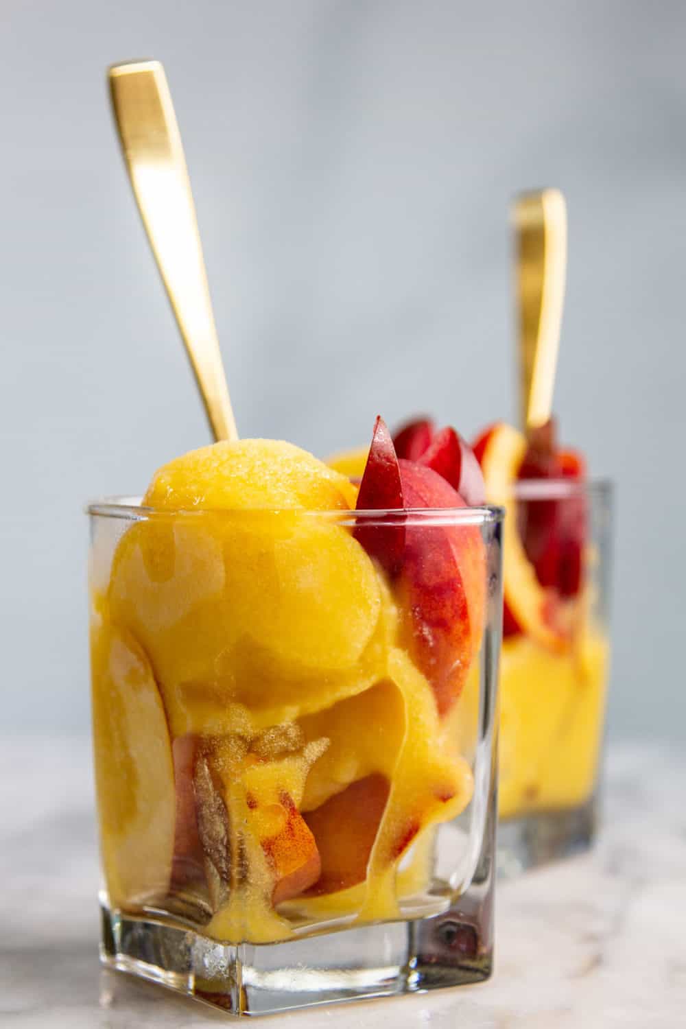 Cups of peach sorbet with slices of stone fruit.