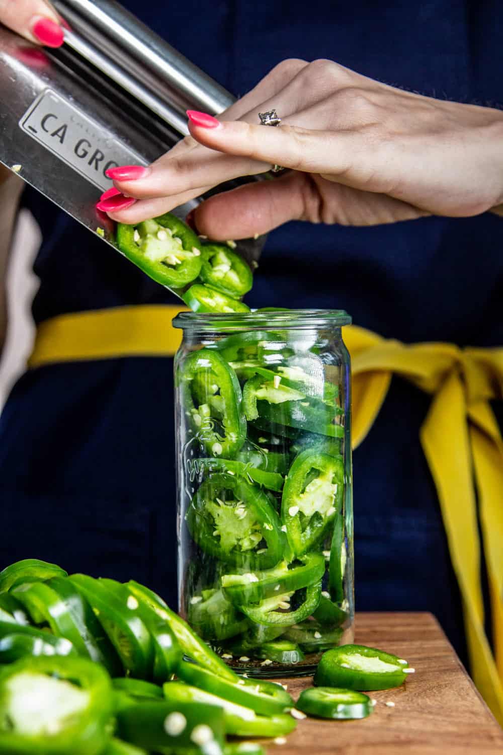 Sliding slices of jalapeno into a jar.