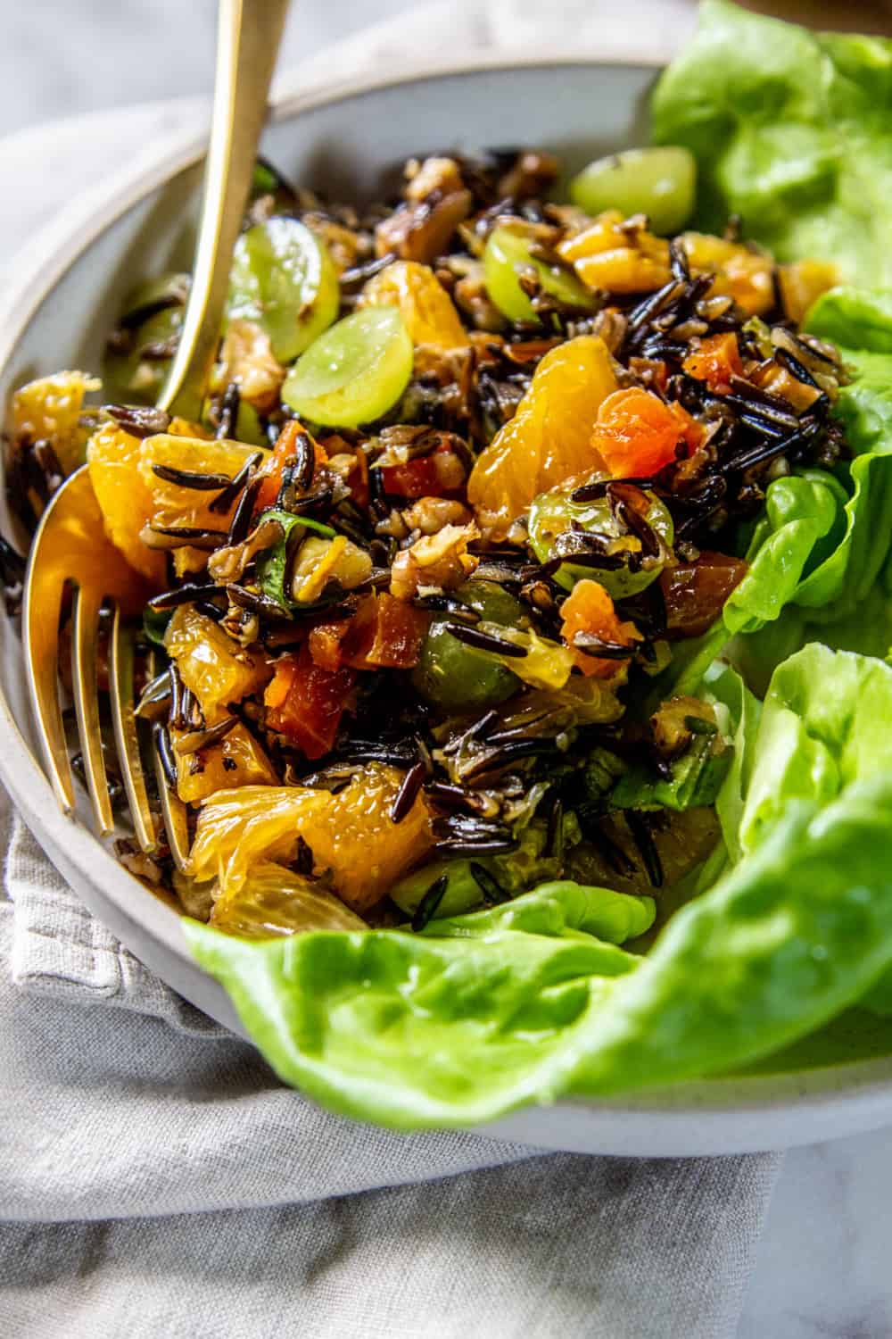 A serving dish with leafy greens and Fruit and Nut-Filled Wild Rice Salad