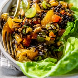A serving dish with leafy greens and Fruit and Nut-Filled Wild Rice Salad